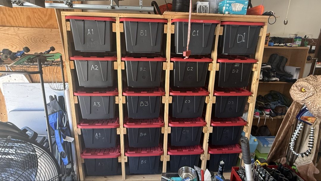 Custom-built wooden bin rack with 27-gallon storage bins labeled A1 through D5 in garage