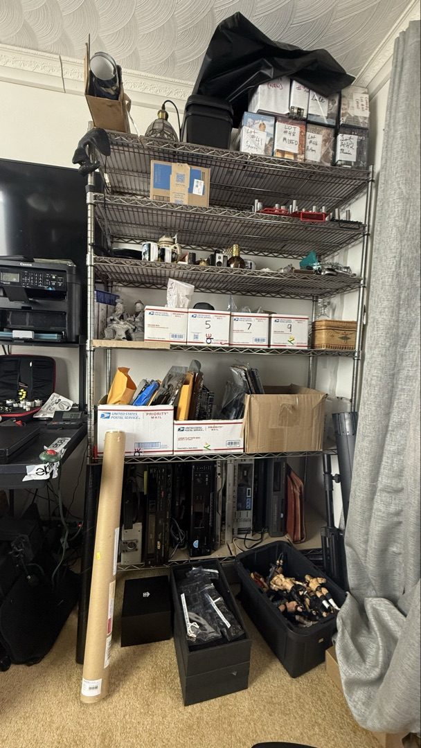 Metal wire shelving unit in office with numbered boxes, socket organizers, and electronics